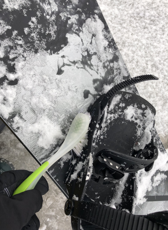 滑り終わった後に、スノーボードの雪をブラシで落としている写真