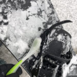 滑り終わった後に、スノーボードの雪をブラシで落としている写真